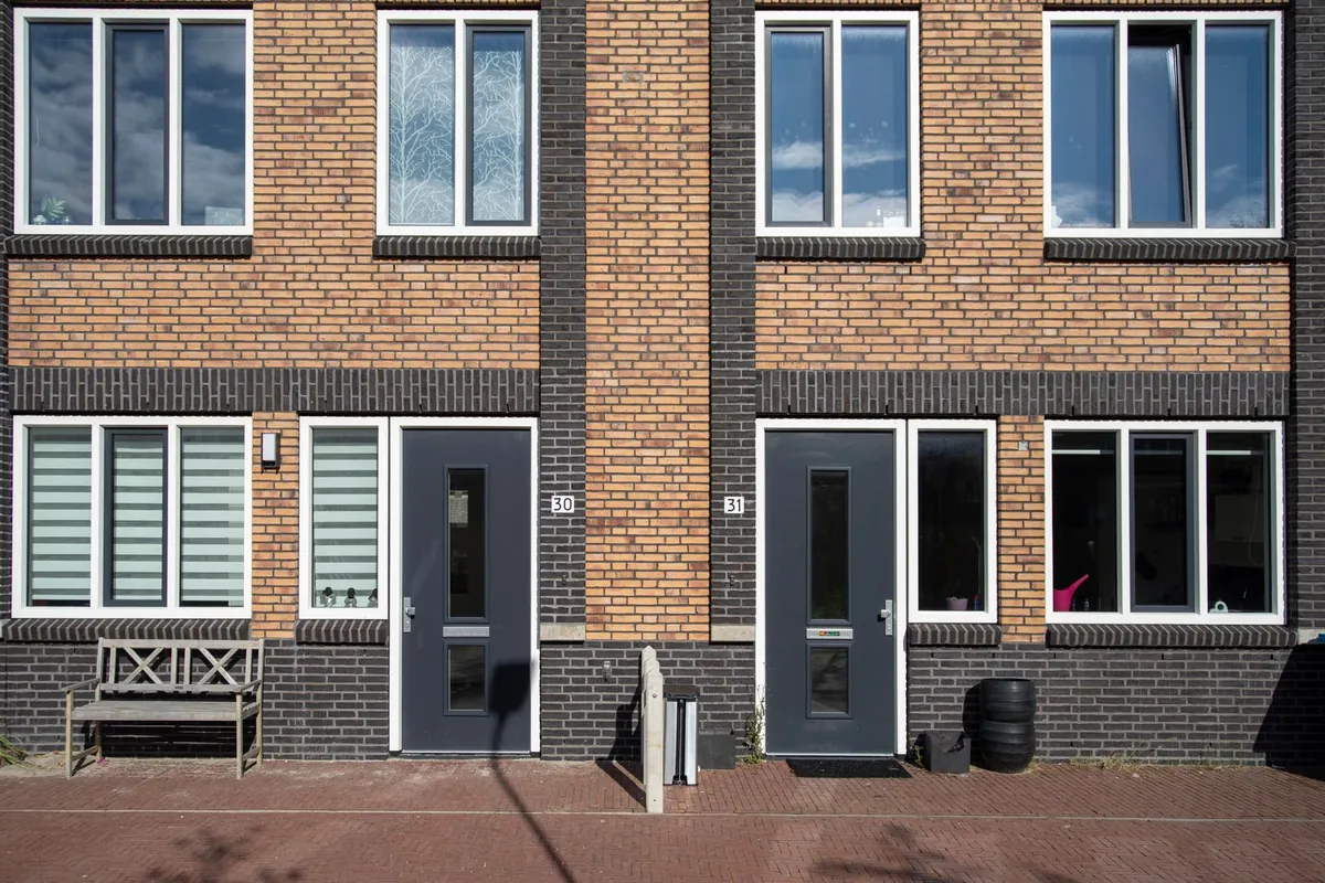 Brick house front with large dark-framed windows and doors